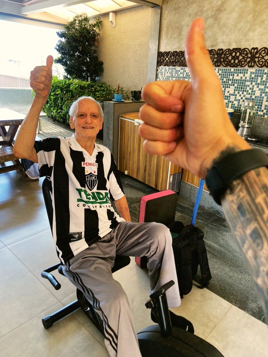 Aluno idoso sorrindo e fazendo joia junto com o personal Pedro Tófani após o treino